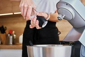 vrouw Koken Bij keuken en gebruik makend van keuken machine foto