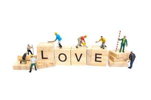 miniatuurarbeiders die het woordliefde bouwen op houten blokken met een witte achtergrond, Valentijnsdagconcept foto