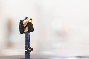 miniatuurreiziger met een rugzak die op lege ruimte, reisconcept loopt foto