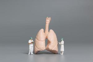 miniatuurdokters en verpleegsters die het concept met menselijke longen, virussen en bacteriën observeren en bespreken