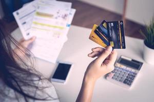 close-up vrouw hand met drie creditcards en papieren aan een bureau met rekenmachine en een mobiele telefoon foto