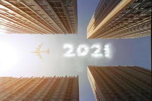 vliegtuig vliegt over wolkenkrabbers om een wolkentekst 2021 in de lucht te maken foto