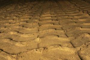 sporen van trekker wielen Aan de zand, betreden merken van trekker banden Aan de zand oppervlakte foto