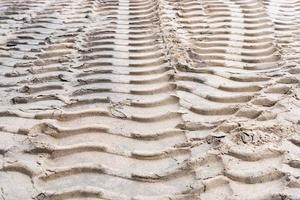 sporen van trekker wielen Aan de zand, betreden merken van trekker banden Aan de zand oppervlakte foto