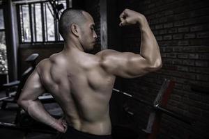 portret van Aziatisch Mens groot spier Bij de sportschool, thailand mensen, training voor mooi zo gezond lichaam gewicht opleiding, geschiktheid Bij de Sportschool begrip, grap naar buik spieren foto