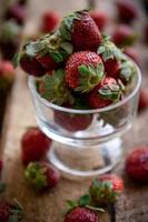 aardbeien in een glas en op een tafel foto