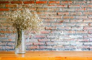 detailopname een mooi bloemen in wijnoogst glas vaas Aan houten tafel en wazig steen muur achtergrond.. foto