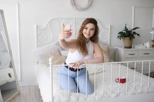 een gelukkig vrouw heeft een selfie. de meisje looks in de telefoon camera en glimlacht. foto