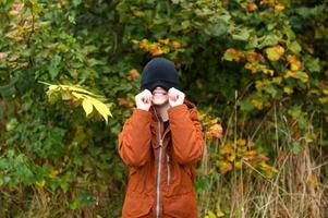 een schattig jongen in een rood jasje getrokken een hoed over- zijn ogen foto