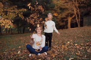 gelukkig meisje en jongen toss geel herfst bladeren in de Woud foto