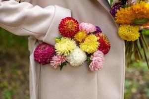 een boeket van herfst bloemen in de zak- van een beige jas foto