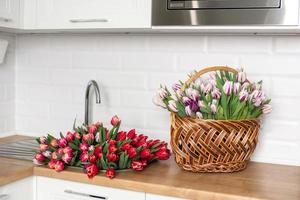 een groot aantal van tulpen van verschillend kleuren leugens Aan de tafel in de keuken. bloemen in de wastafel foto