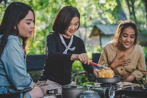 jong vrouw Koken met ei terwijl camping met meisje vriend foto