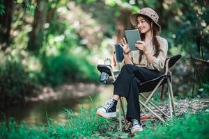 jong vrouw gebruik tablet video telefoontje terwijl camping in park foto