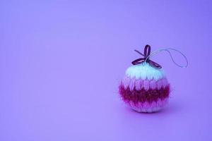 gebreid, zacht, gekleurde handgemaakt Kerstmis bal Aan een licht Purper achtergrond foto