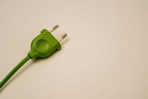 groen elektrisch draad en plug Aan een licht perzik achtergrond foto