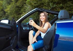 glimlachen Kaukasisch vrouw met mobiele telefoon in een auto foto