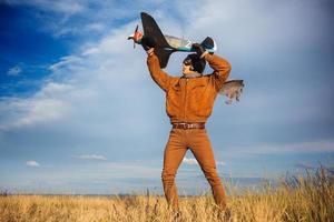 vent in wijnoogst kleren piloot met een vliegtuig model- buitenshuis foto