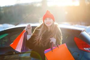 glimlachen Kaukasisch vrouw Holding haar boodschappen doen zak in de buurt de auto foto