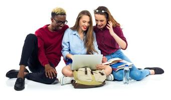 drie gelukkig studenten zittend met boeken, laptop en Tassen foto