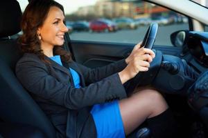 vrouw in een blauw jurk en jasje gebruik makend van een smartphone in de auto foto