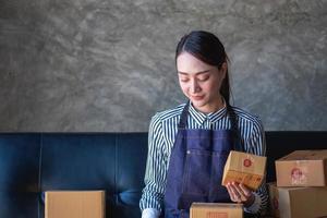 Aziatisch vrouw ondernemer beginnend een online verkoop bedrijf gebruik makend van laptops, tabletten, en smartphones naar plaats bestellingen en controleren producten binnen haar eigen kantoor, mkb online concept. foto