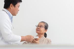 Aziatisch mannetje dokter uitleggen geneeskunde naar ouderen vrouw geduldig in ziekenhuis. foto