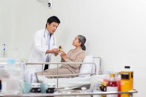 Aziatisch mannetje dokter uitleggen geneeskunde naar ouderen vrouw geduldig in ziekenhuis. foto