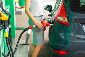 vrouw vult benzine in de auto Bij een gas- station foto