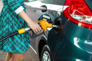 vrouw vult benzine in haar auto Bij een gas- station foto