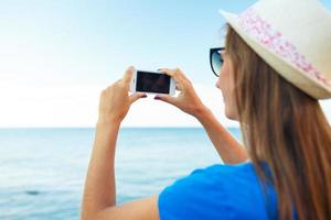 meisje in hoed maken foto's van de adriatisch zee door de smartphone foto