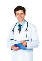 portret van glimlachen jong mannetje dokter schrijven Aan een patiënten medisch tabel Aan wit foto