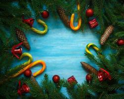 Kerstmis grens met Spar boom takken, kegels, Kerstmis decoraties en snoep riet Aan blauw houten borden foto