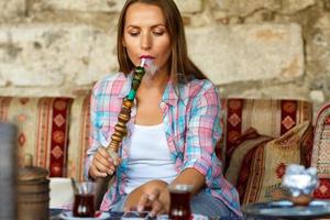 vrouw roken een hookah en toepassingen smartphone in een cafe in Istanbul, kalkoen foto