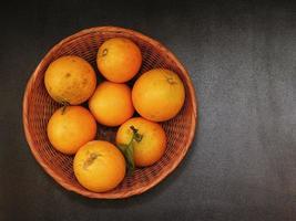 mandarijnen in een rieten kom op een donkere tafelachtergrond foto