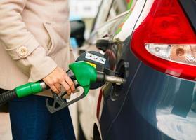 vrouw vult benzine in haar auto Bij een gas- station foto
