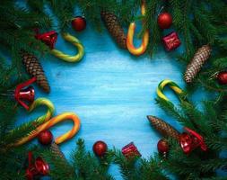 Kerstmis grens met Spar boom takken, kegels, Kerstmis decoraties en snoep riet Aan blauw houten borden foto