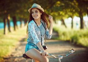 lief jong vrouw in een hoed rijden een fiets buitenshuis. actief mensen foto