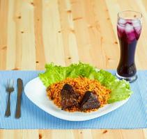 smakelijk schotel van gebraden rundvlees met rijst- en salade bladeren en een glas van sap met ijs foto
