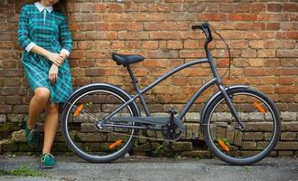 zwart fiets en een meisje in de buurt het Aan de oud steen muur achtergrond foto