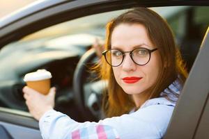 jong vrouw met koffie naar Gaan het rijden haar auto foto