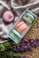 roze en munt Frans bitterkoekjes of macarons koekjes in geschenk doos en een lila bloemen Aan een kleding en rietje staan achtergrond. natuurlijk fruit en BES smaken, romig vulling voor valentijnsdag, moeder dag foto