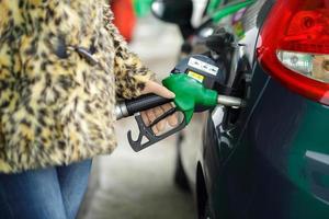 vrouw vult benzine in haar auto Bij een gas- station in winter foto