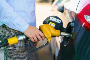 vrouw vult benzine in de auto Bij een gas- station foto
