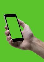 mannetje hand- Holding zwart mobiele telefoon met groen croma scherm Bij geïsoleerd groen achtergrond. foto
