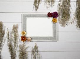 top visie van leeg foto kader met droog kleurrijk bloemen over- een wit houten tafel