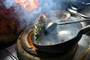 een chef in xinjiang is frituren een lekkernij snel, de vlammen zijn vliegend en de aroma is overlopend foto