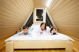 kinderen in zacht warm pyjama spelen Bij houten cabine huis. concept van jeugd, vrije tijd werkzaamheid, geluk. broer en zussen hebben pret en spelen samen. foto