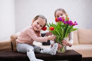 twee zussen met voorjaar tulp boeket. vakantie decor met bloemen kleurrijk tulpen. foto