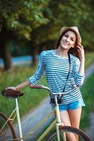 lief jong vrouw in een hoed met een fiets in een park foto